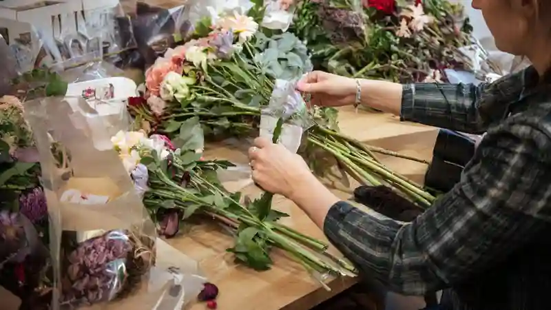 Руки флориста, собирающего букет за рабочим столом